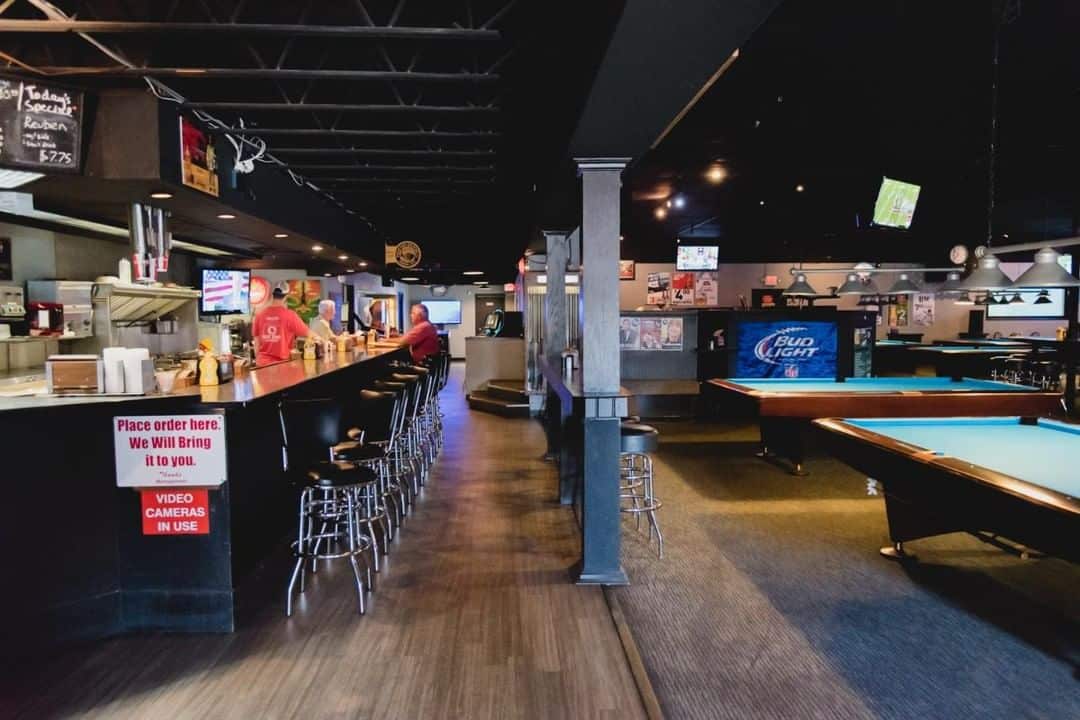 The inside of Billiards of Springfield with the bar on one side and pool tables set up on the other side.