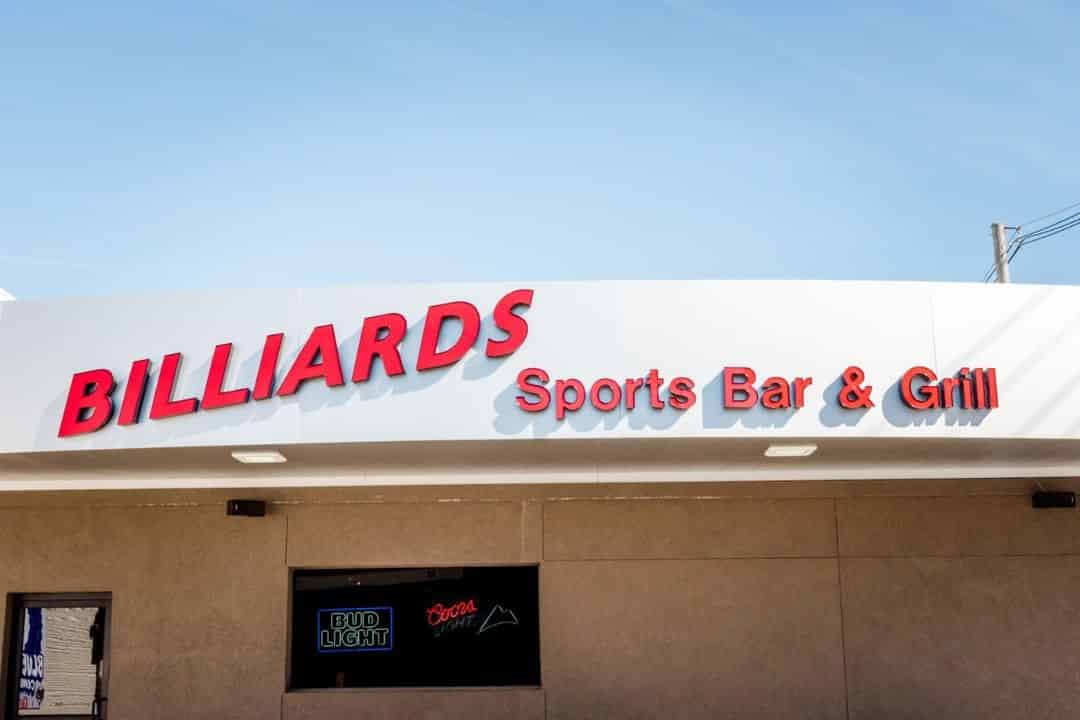 Sign on outside of bar that reads "Billiards Sports Bar and Grill"